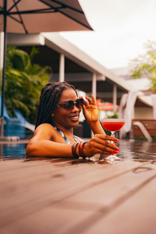 a woman sitting in a pool holding a drink at ONOMO Hotel Abidjan in Abidjan