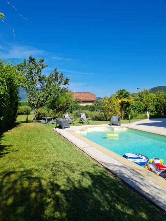 - une piscine dans une cour avec 2 chaises longues dans l'établissement Maison Familiale avec piscine, à Aix-les-Bains