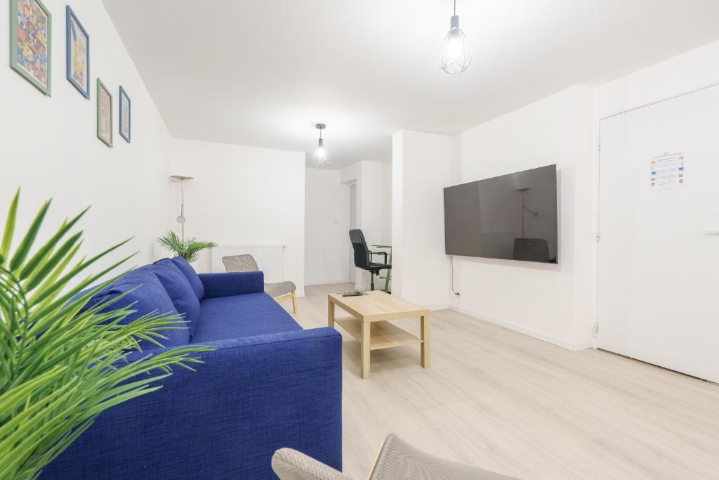 un salon avec un canapé bleu et une télévision dans l'établissement La Suite du Château B - En plein centre, à Lunéville