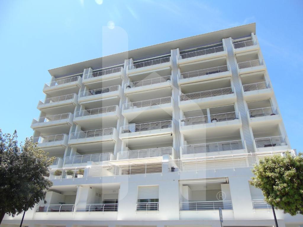 ジュリアノーヴァにあるHomiday - Riviera Palaceのバルコニーと木々が備わる白いアパートメントです。