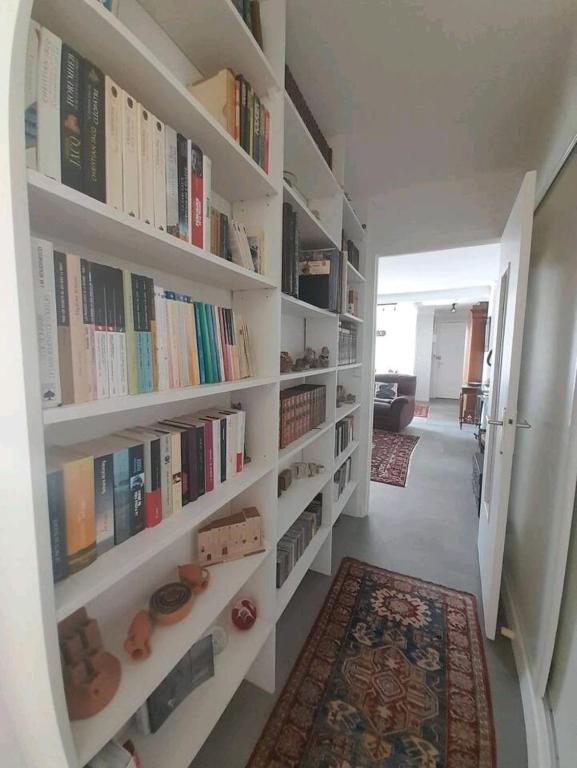 un couloir avec des étagères blanches remplies de livres dans l'établissement T3 hyper centre- ascenseur- parking- balcon, à Châteauroux