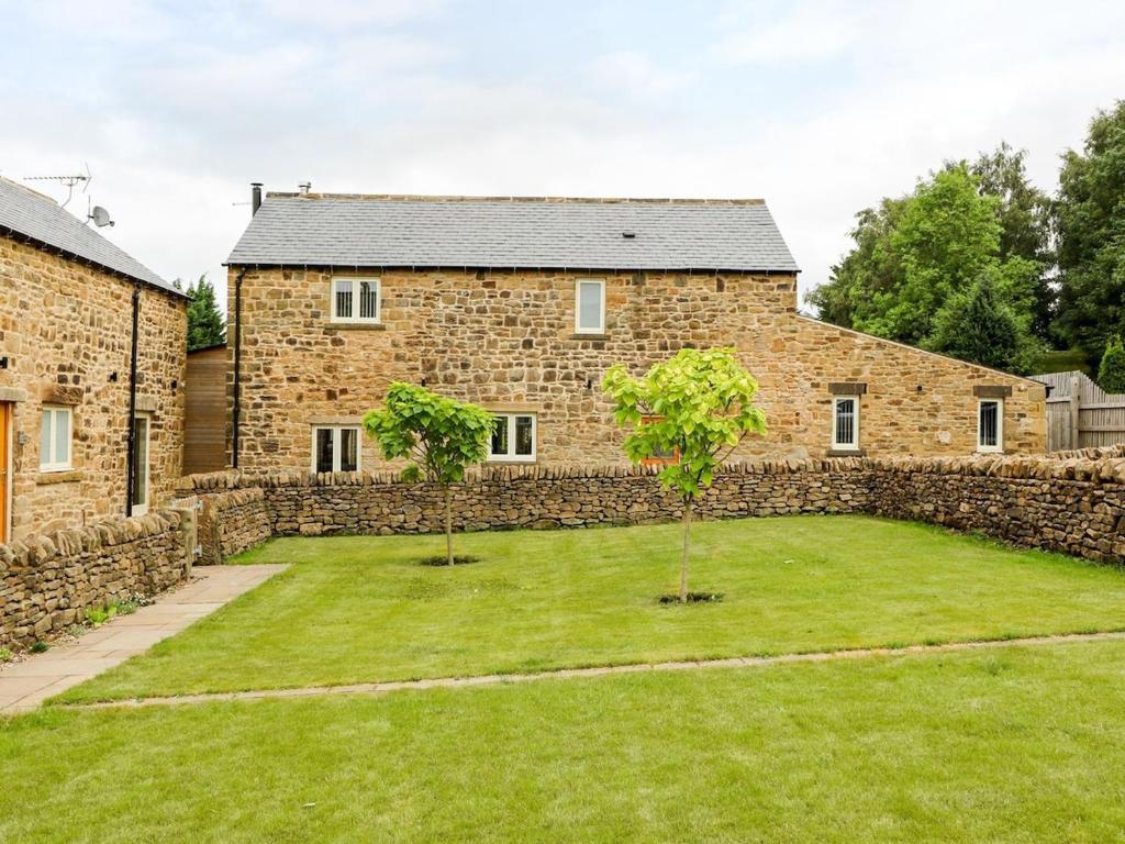 two trees in a yard in front of a stone building at Beautiful Stone Barn with Hot Tub on a Quiet Farm in Eckington