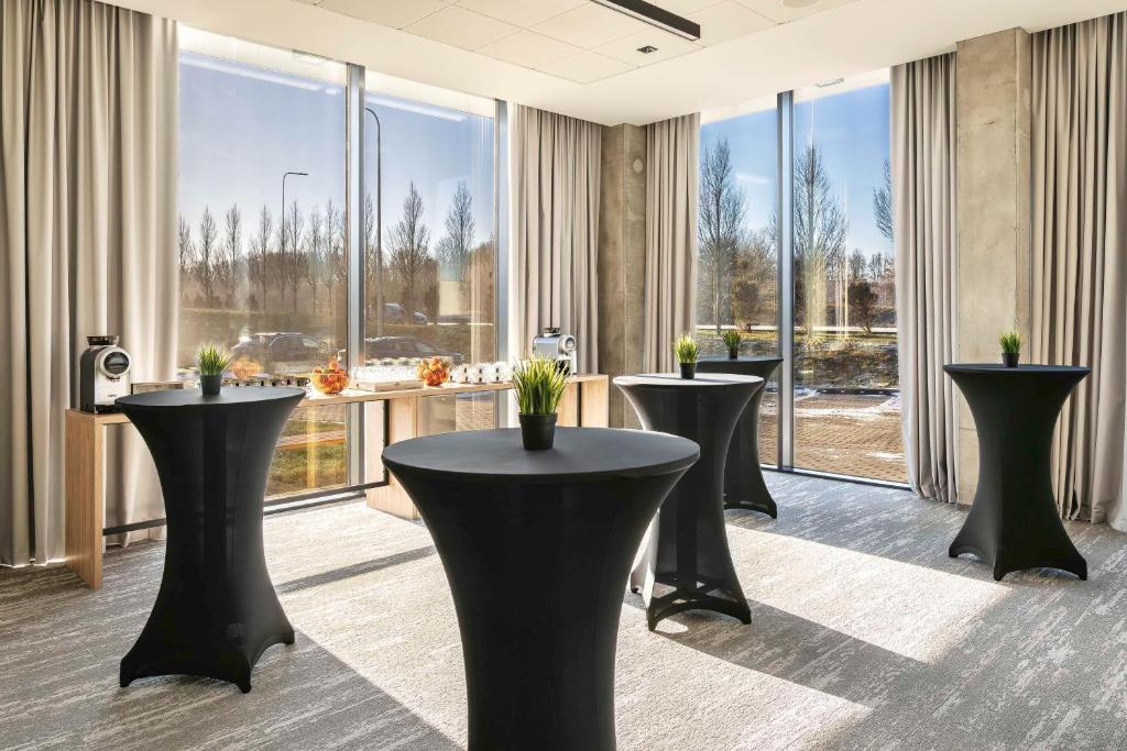 a room with four black tables and large windows at Park Inn by Radisson Vilnius Airport Hotel & Conference Centre in Vilnius