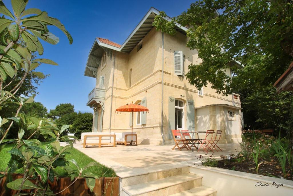 Cette maison dispose d'une terrasse avec des chaises et un parasol. dans l'établissement Villa familiale rénovée à Arcachon avec 6 ch, 4 sdb, entre 8 à 10 pers, à Arcachon