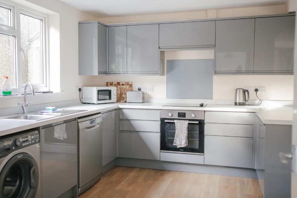 a kitchen with white cabinets and a dishwasher at Entire 3 bedroom house, SALISBURY Cathedral City in Salisbury