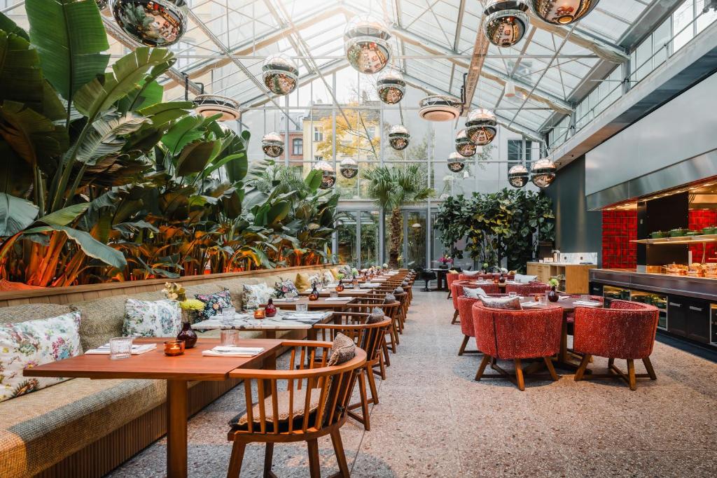 ベルリンにあるsly Berlinのテーブルと椅子、植物のあるレストラン