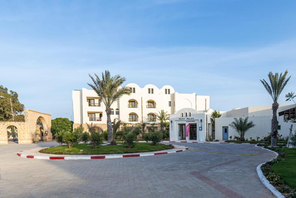 乌姆苏克Le Petit Palais Djerba & Spa的一座白色的大建筑,前面有棕榈树