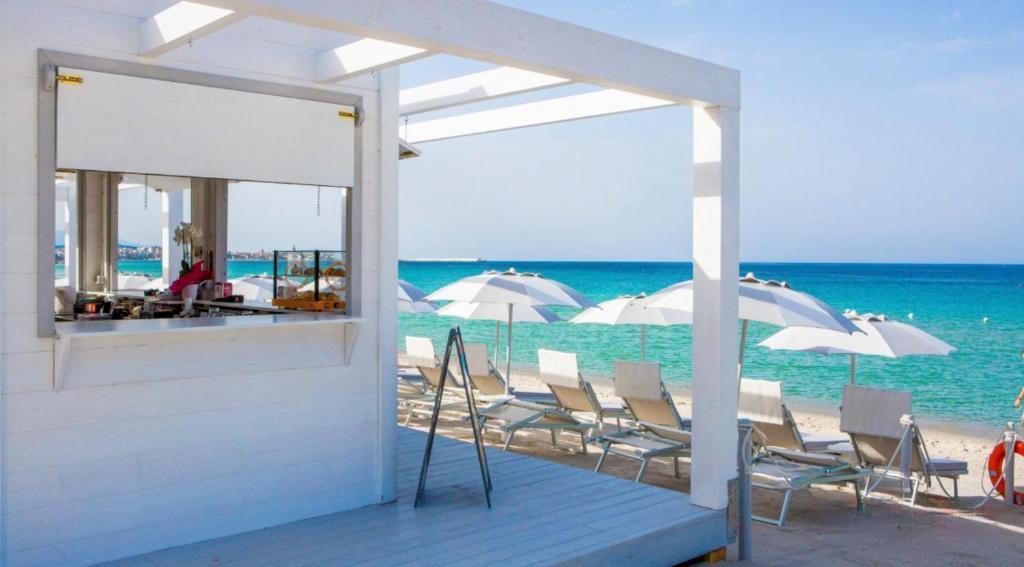 een groep stoelen en parasols op een strand bij Villa Le Dune a few steps from the sandy beach of Maria Pia in Alghero