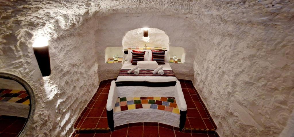 a bedroom with a bed in a stone cave at Casa CUEVA CASCAMORRAS "Capricho Andaluz" in Baza