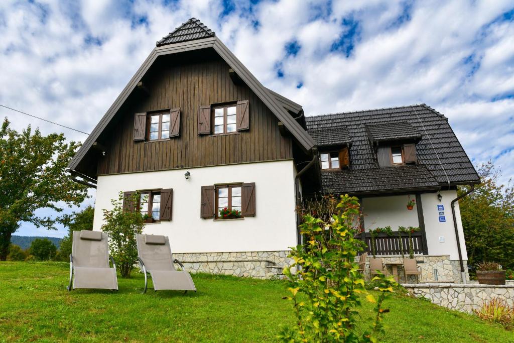 a white house with a black roof and two chairs at FLORA HOUSE in Rastovača