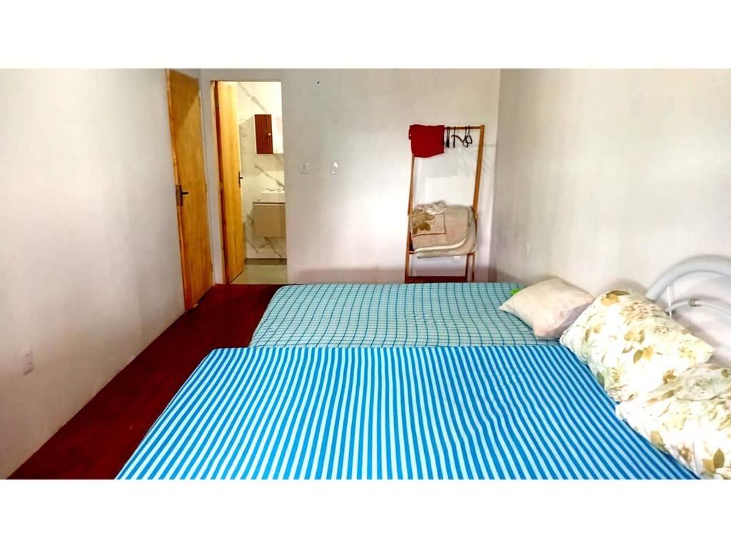 a small bedroom with a bed with blue and white stripes at Casa da família Castro in Capão da Canoa