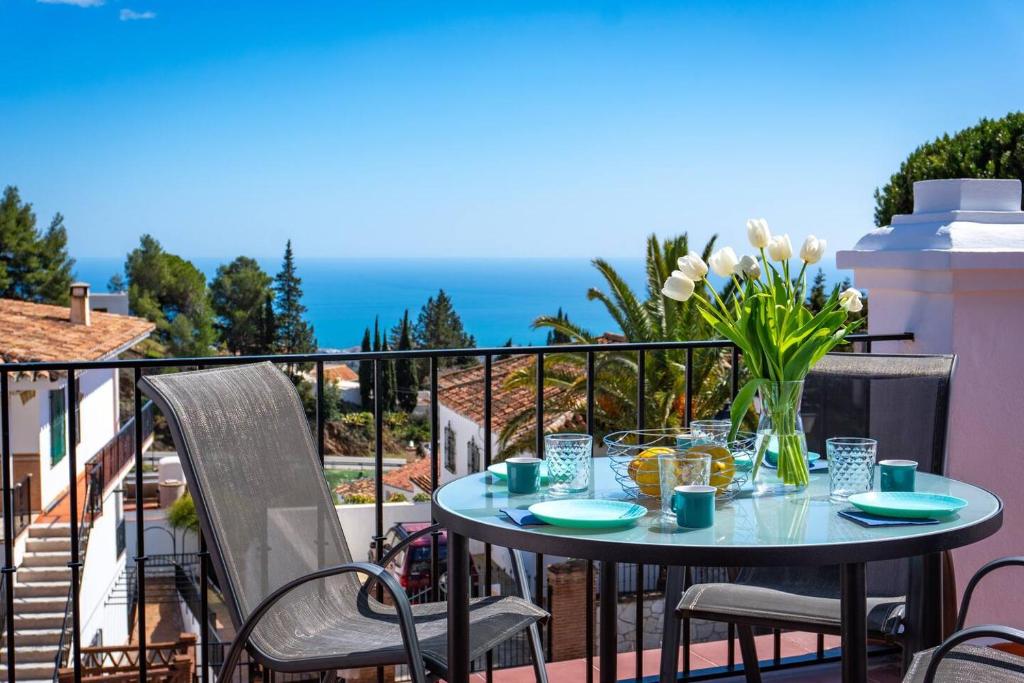 a table with a vase of flowers on a balcony at Idyllic Townhouse with Scenic Views Mijas Pueblo in Mijas