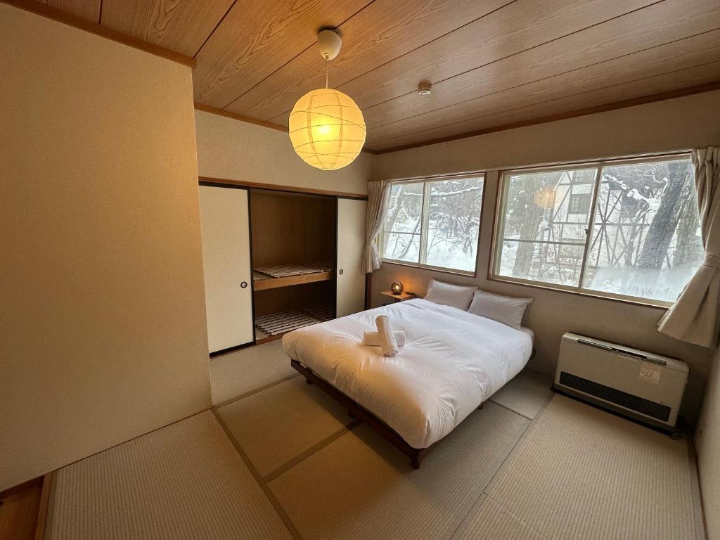 una camera con letto bianco in una stanza con finestre di Hakuba Third Place Lodge a Hakuba