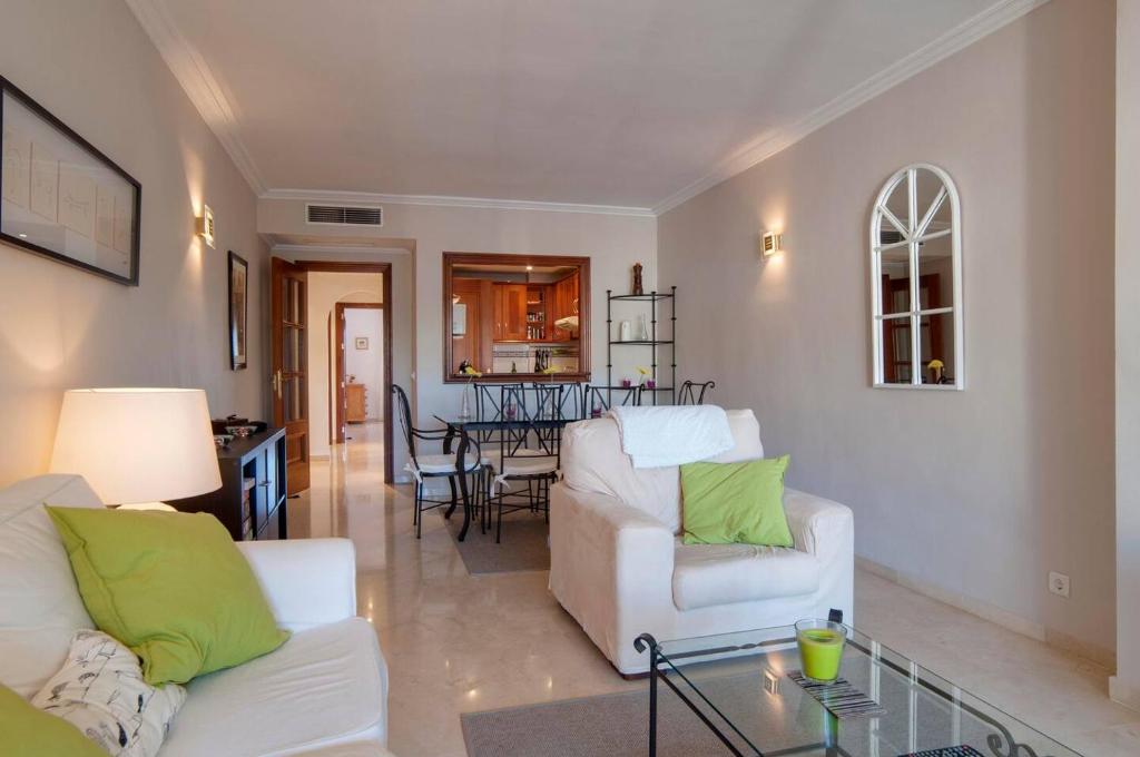 salon z 2 białymi krzesłami i stołem w obiekcie Sunny Terrace Apartment In Prestigious Mijas Golf w mieście Mijas