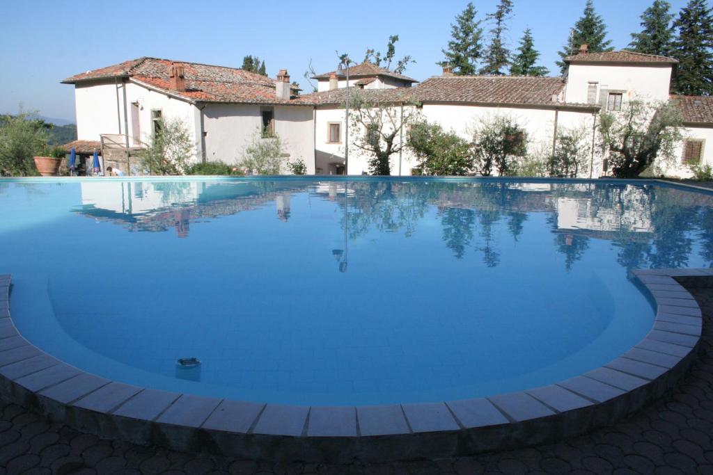 una grande piscina con acqua blu di fronte a una casa di Villa Grassina a Pelago