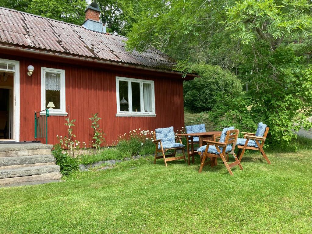 une table et des chaises devant une maison rouge dans l'établissement Lilla Halängen cottages, Mormors hus, à Dalskog