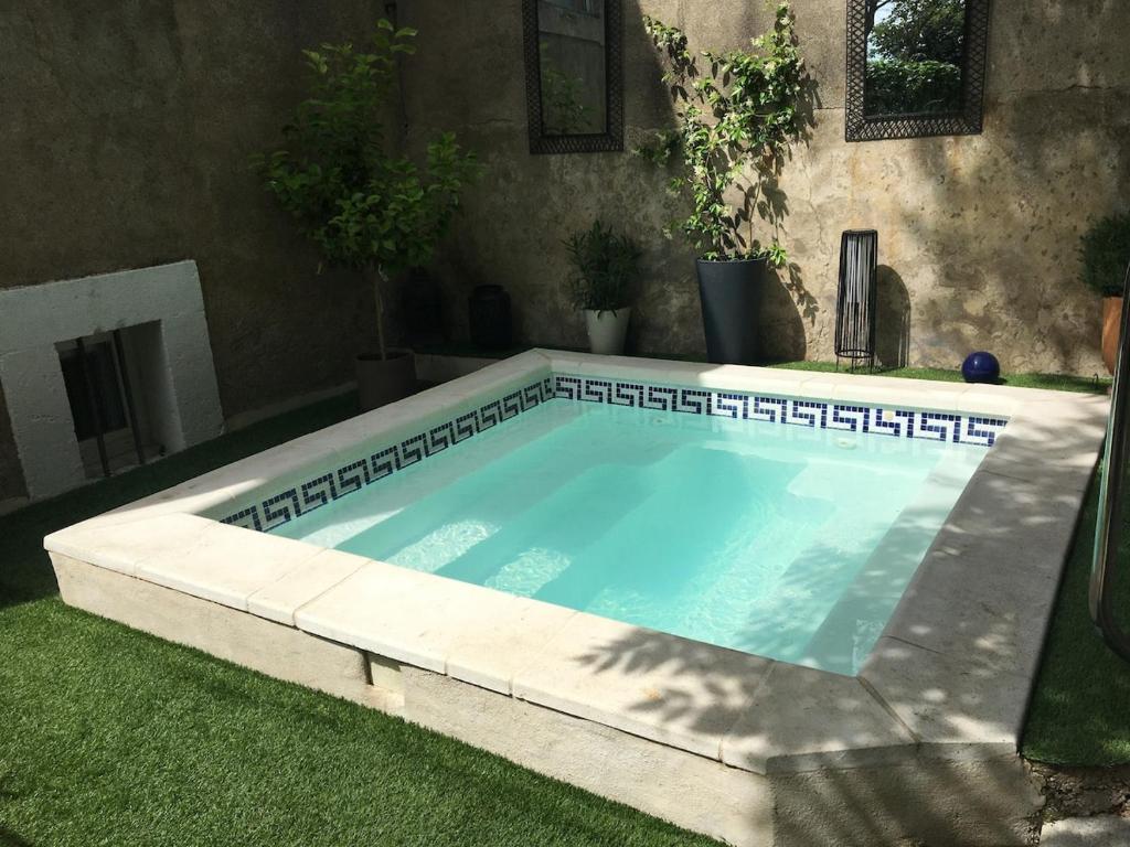 - une piscine dans une cour avec gazon dans l'établissement L'Oustalou, à Béziers