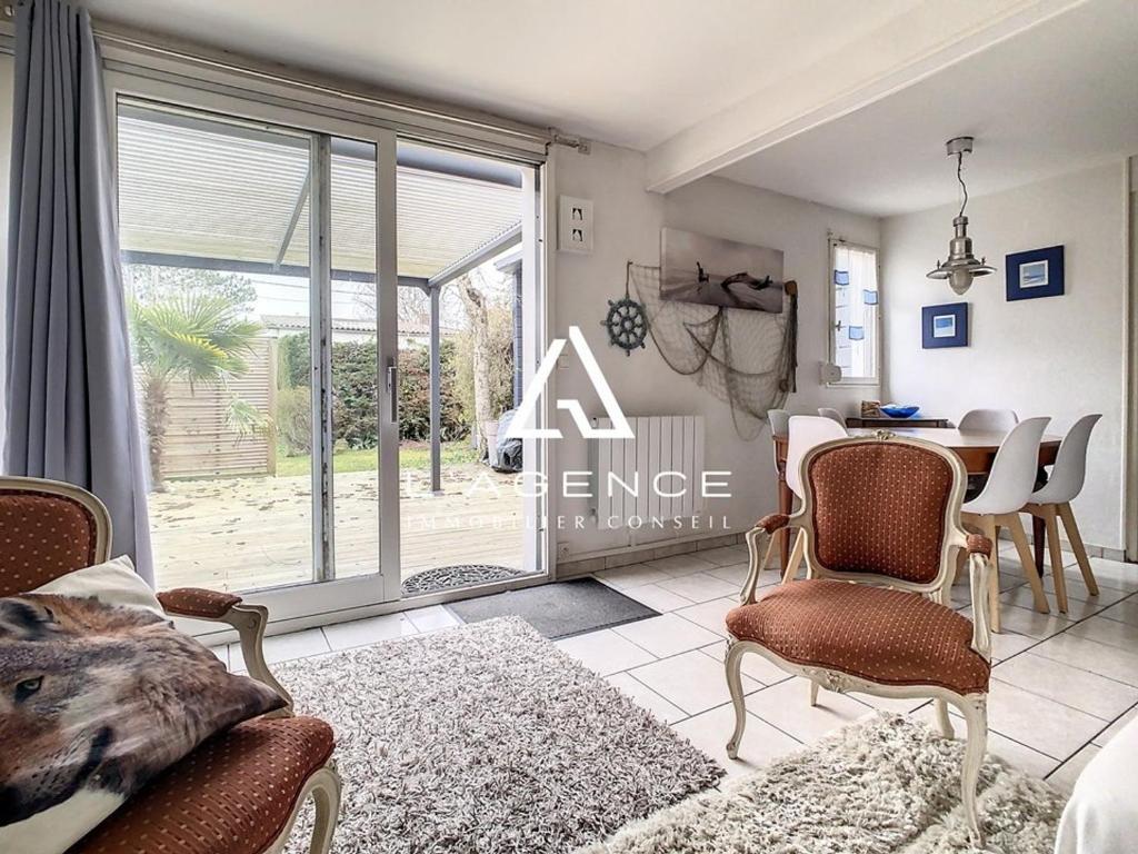 - un salon avec une table, des chaises et une grande fenêtre dans l'établissement Maison 3 chambres avec terrasse, animaux admis, parking - FR-1-236-132, à Merlimont