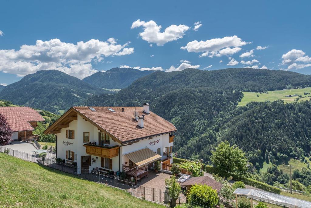 a house on a hill with mountains in the background at Familyapartment Alpe - Unterkehrhof in Laion