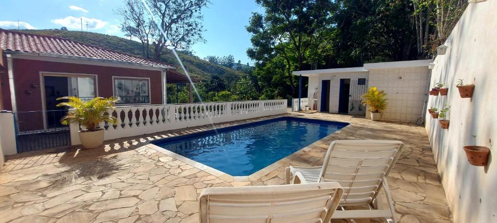 a swimming pool with chairs and a house at Recanto Águas Claras in Soledade de Minas