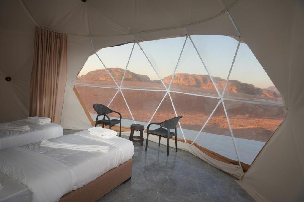 a room with two chairs and a large window at Tulip Camp Wadi Rum in Wadi Rum