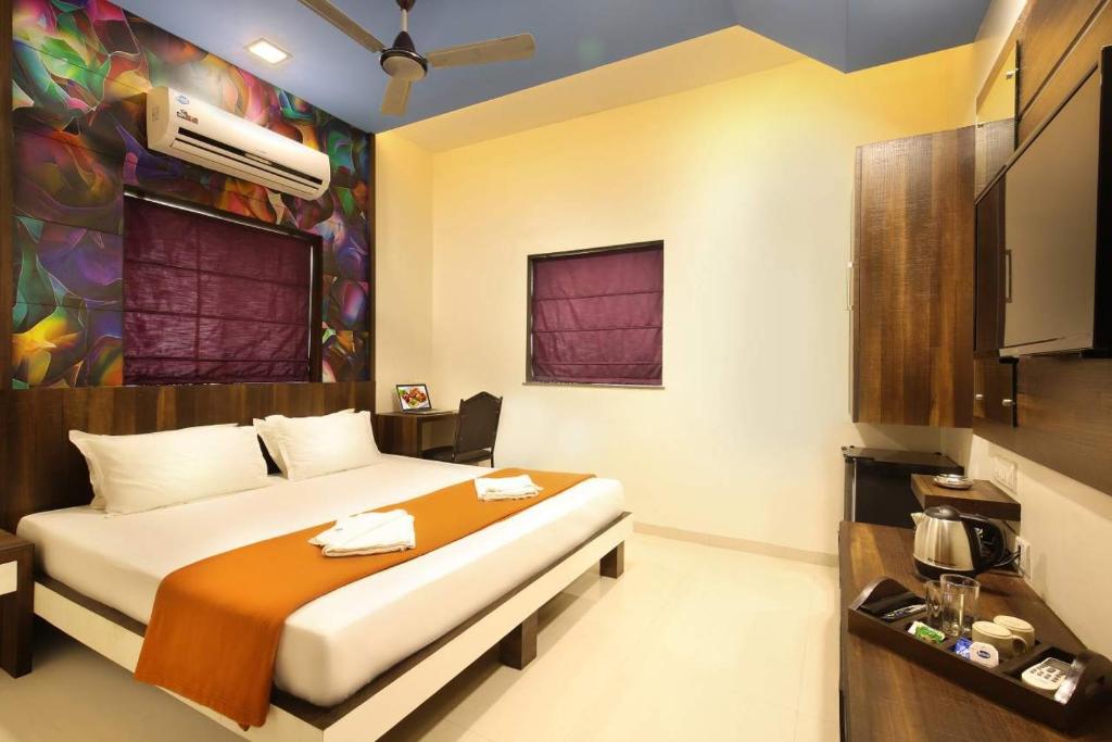 a hotel room with a bed and a tv at Hotel Lonavla in Lonavala