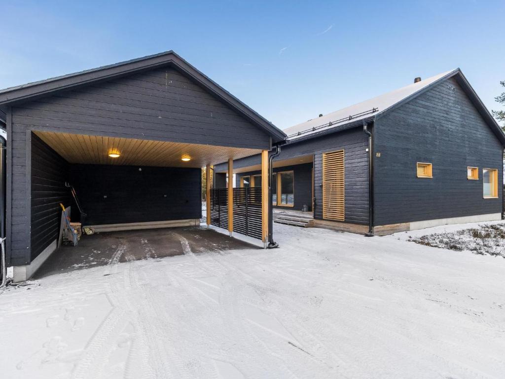 a building with a garage with snow on the ground at Holiday Home Villa plywood by Interhome in Syöte