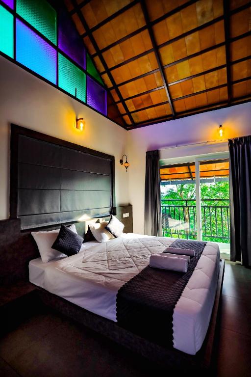 a bedroom with a large bed with a large window at La Vista Resorts in Wayanad