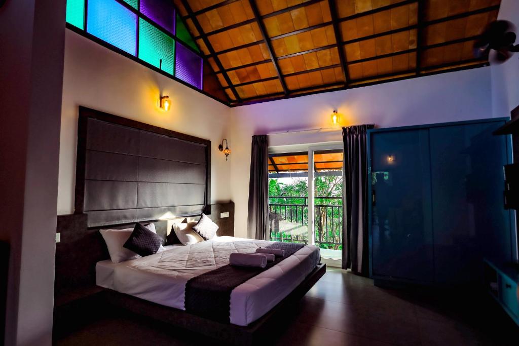a bedroom with a bed and a large window at La Vista Resorts in Wayanad