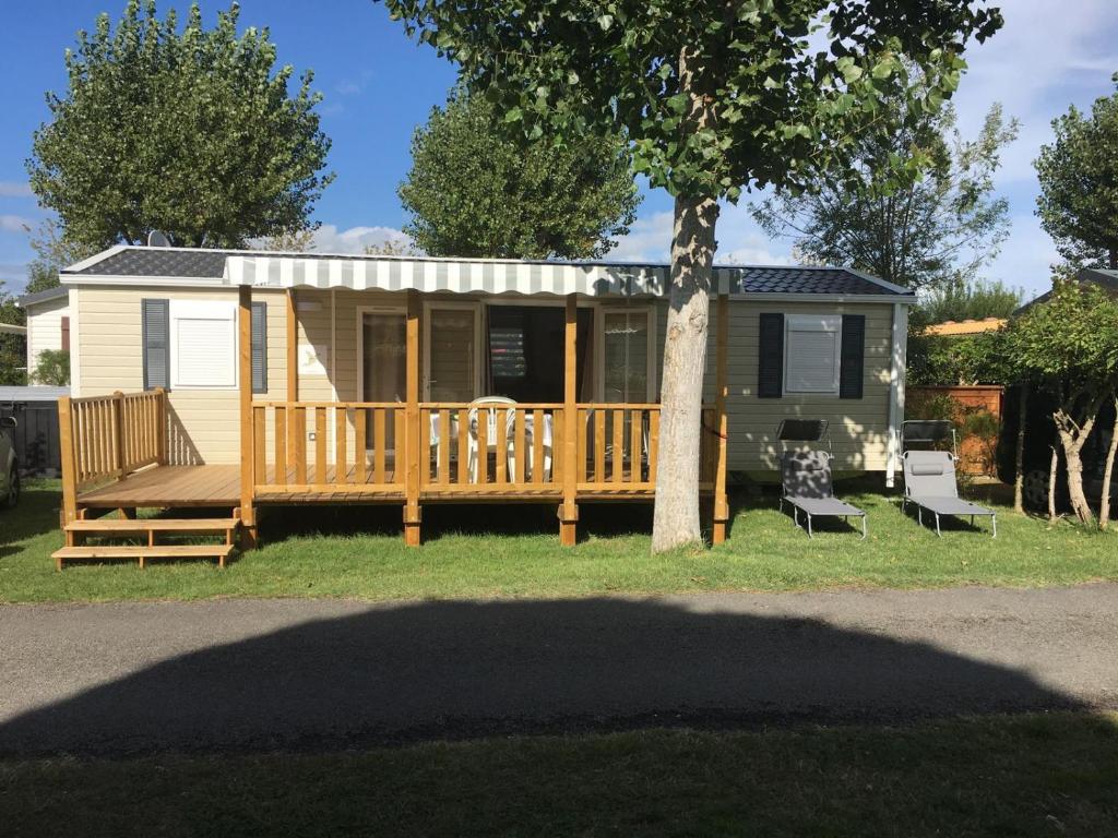 une petite maison avec un porche et une terrasse dans l'établissement MH climatisé 4P camping La Yole St Jean de Monts, à Saint-Jean-de-Monts