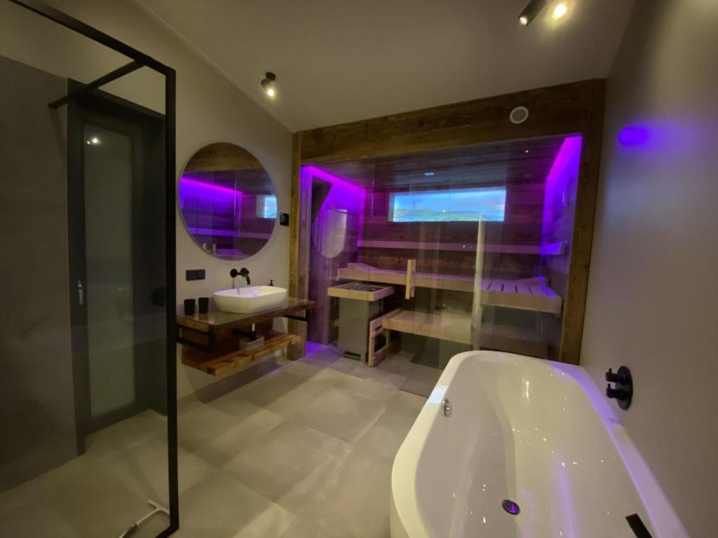 ein Badezimmer mit einer Badewanne und einem Waschbecken mit violetten Lichtern in der Unterkunft Holiday Home Seascape Wellness Nieuwvliet-Bad by Interhome in Nieuwvliet-Bad