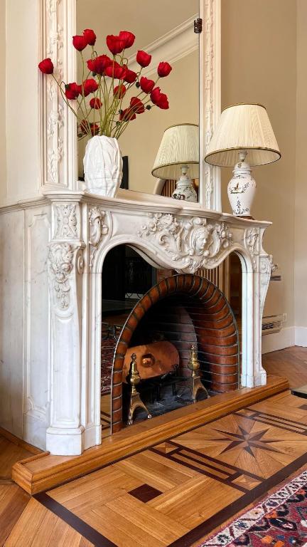 une cheminée avec un manteau blanc et des roses rouges dans l'établissement Le vintage, à Bouzigues