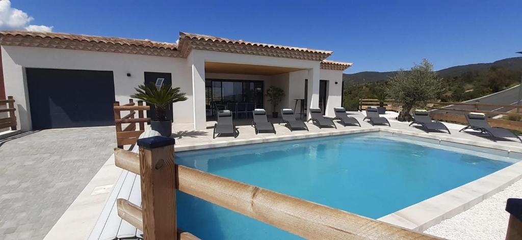une piscine avec des chaises et une maison dans l'établissement Villa neuve 4 étoiles avec piscine et belles vues, à Sainte-Maxime