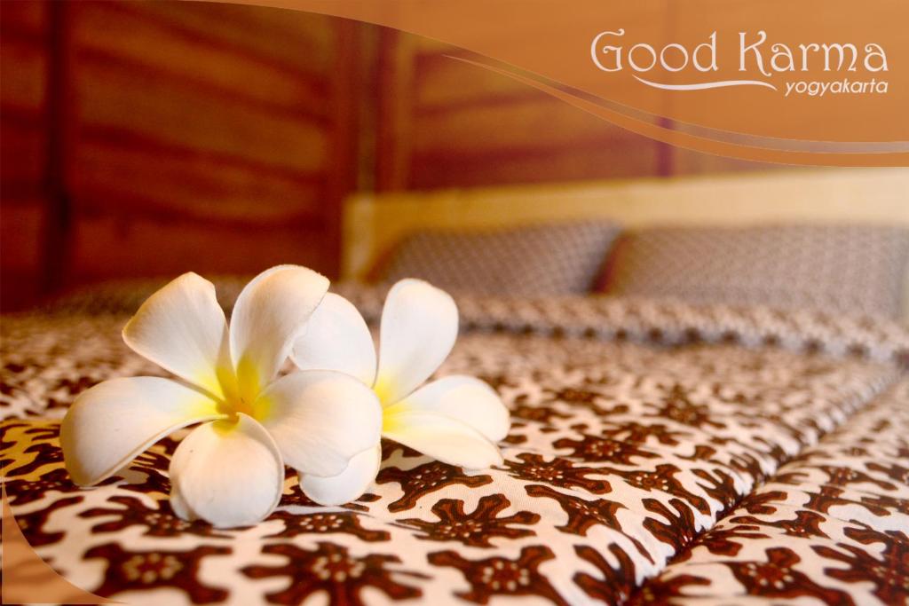zwei weiße Blumen auf einem Bett in der Unterkunft Good Karma Yogyakarta in Yogyakarta