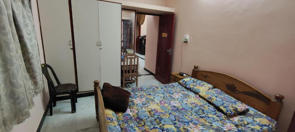 ein kleines Schlafzimmer mit einem Bett und einem Stuhl in der Unterkunft White Town Home Stay in Puducherry