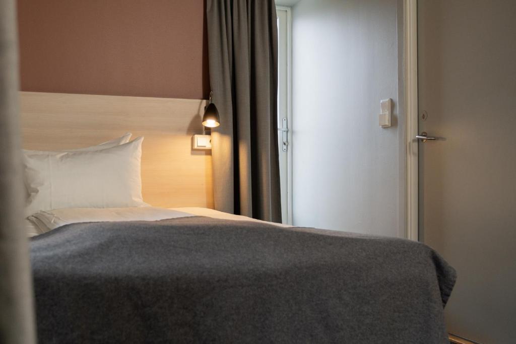 a bedroom with a bed and a door with a window at Citybox Oslo in Oslo