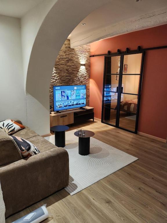 un salon avec un canapé et une télévision à écran plat dans l'établissement Escapade sur la Sorgue, à LʼIsle-sur-la-Sorgue