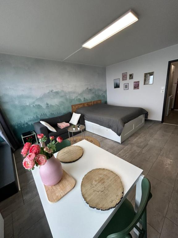 a room with a bed and a table with flowers on it at Le Panorama - GÎTES MARCK in Turckheim