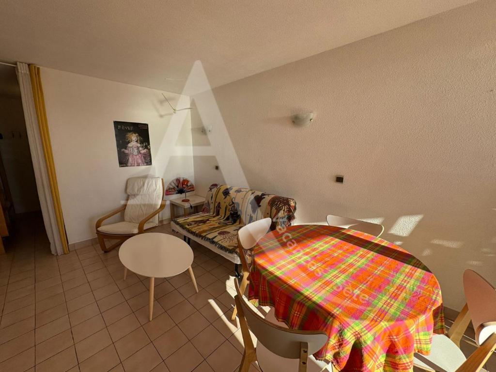 - un salon avec une table, des chaises, une table et des chaises dans l'établissement Studio cabine 4 personnes vue jardin dans residence avec piscine, à Sète