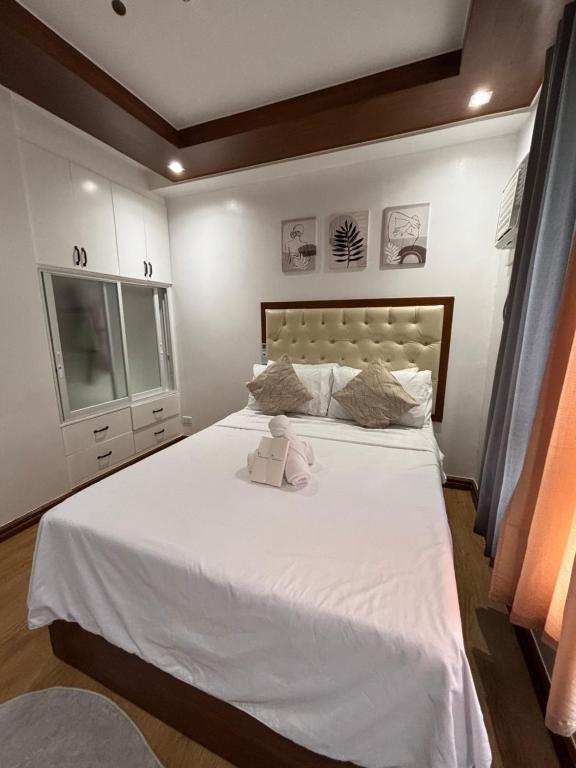 a bedroom with a white bed with a teddy bear on it at Cozy Condo in Davao City in Davao City