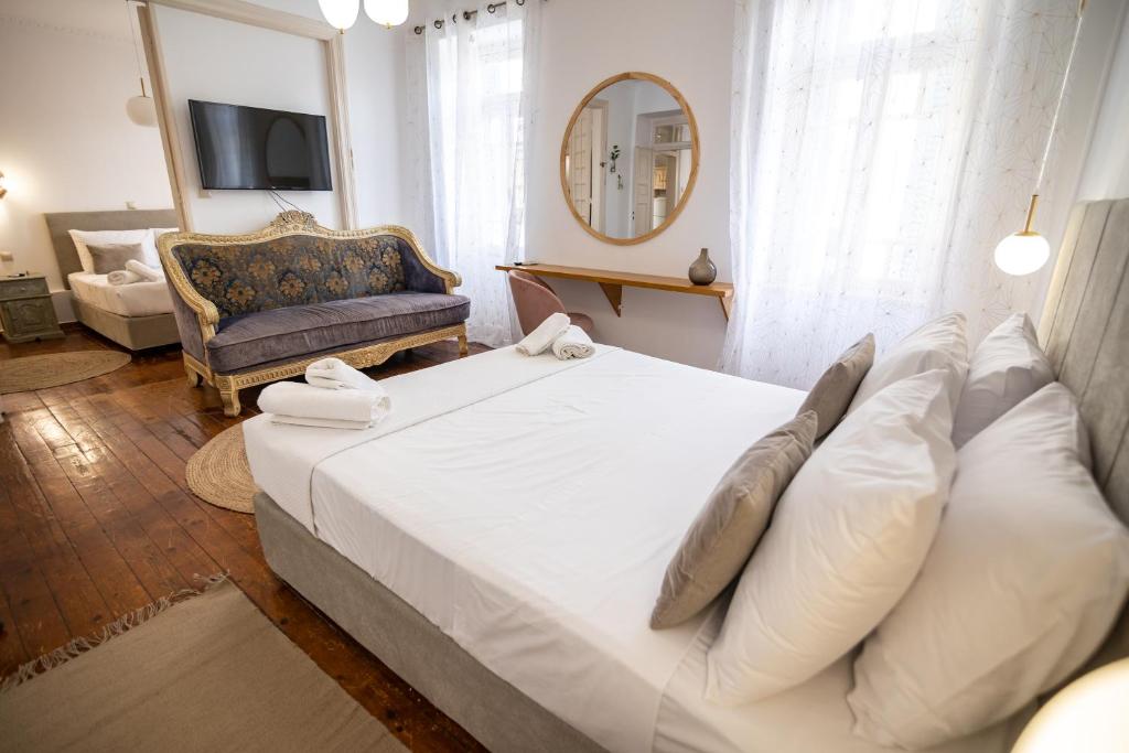 a bedroom with a large white bed and a couch at Apeiron Acropolis Suites in Athens