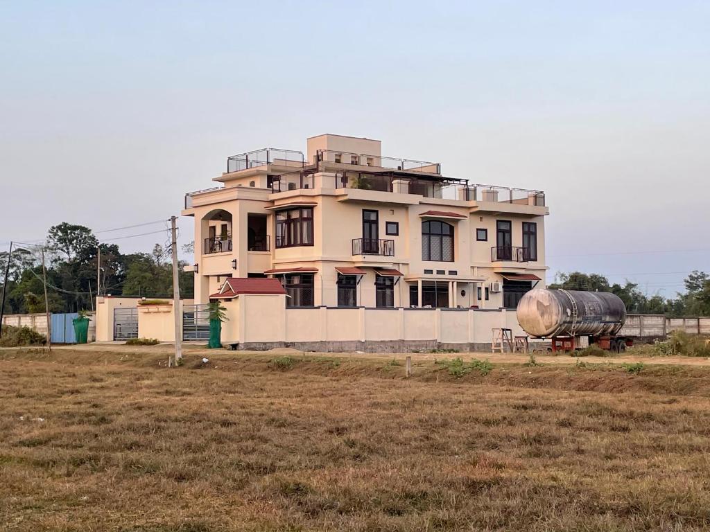 迪布鲁加尔Dibru Ghar Homestay的田野前有坦克的建筑物