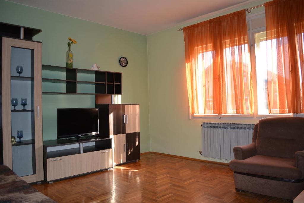 a living room with a flat screen tv and a chair at Guest house Ema in Daruvar