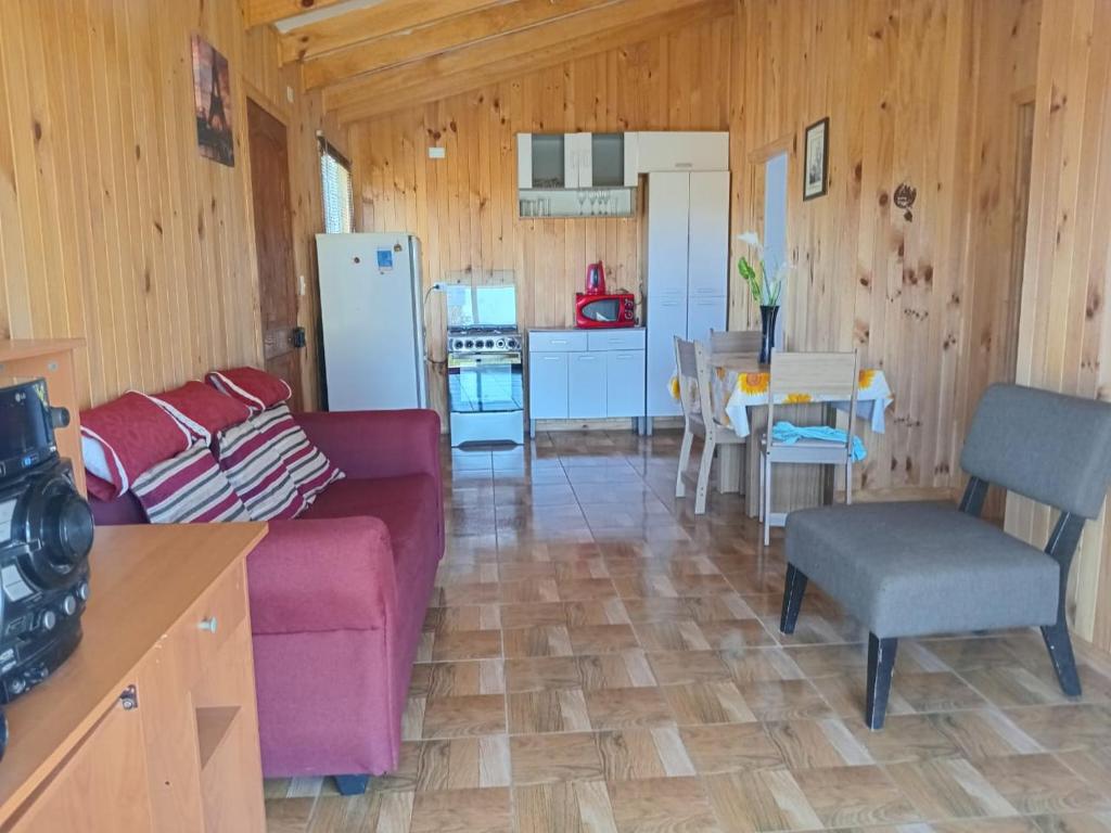 a living room with a couch and a table and a kitchen at Cabaña San Isidro in Coipue
