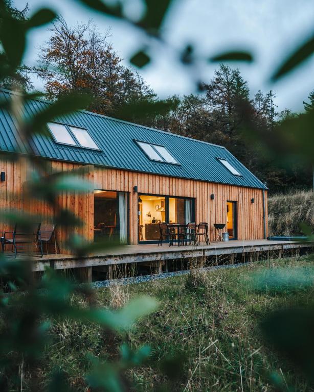 a wooden house with a blue roof and windows at Forest Corner Luxury Home with Hot Tub in North Ballachulish