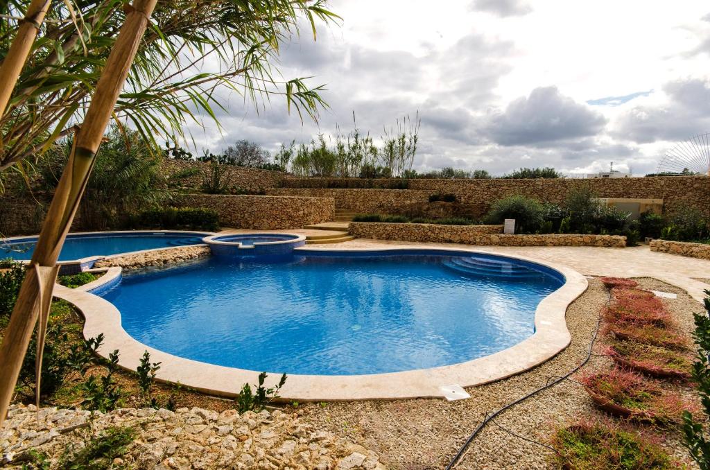 una piscina en un jardín con palmeras en GozoPride Penthouse, en Qala
