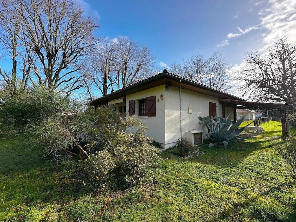 une petite maison blanche dans un champ arboré dans l'établissement Villa 4 pièces, 3 chambres, grand terrain paysagé, à Gujan-Mestras