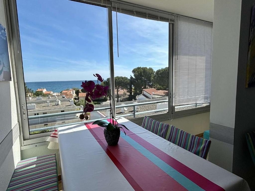Cette chambre comprend une table avec un vase et des fleurs. dans l'établissement Appartement deux pièces cabine - Argelès sur mer AR360-114, à Argelès-sur-Mer