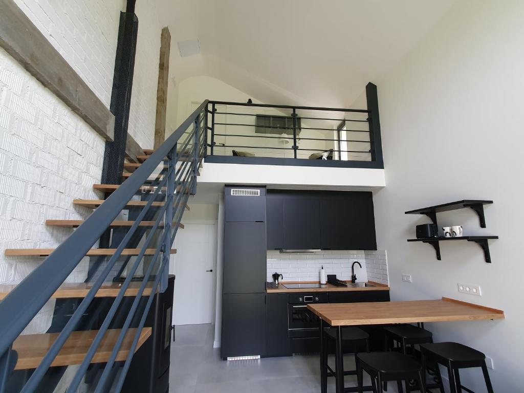 a loft kitchen with a staircase and a table at Apartamentos Islas Pantorgas in Tapia de Casariego