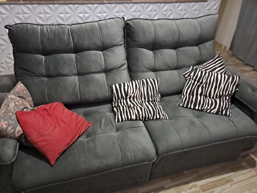 a black leather couch with three pillows on it at Casa Grande na zona sul in Sao Paulo